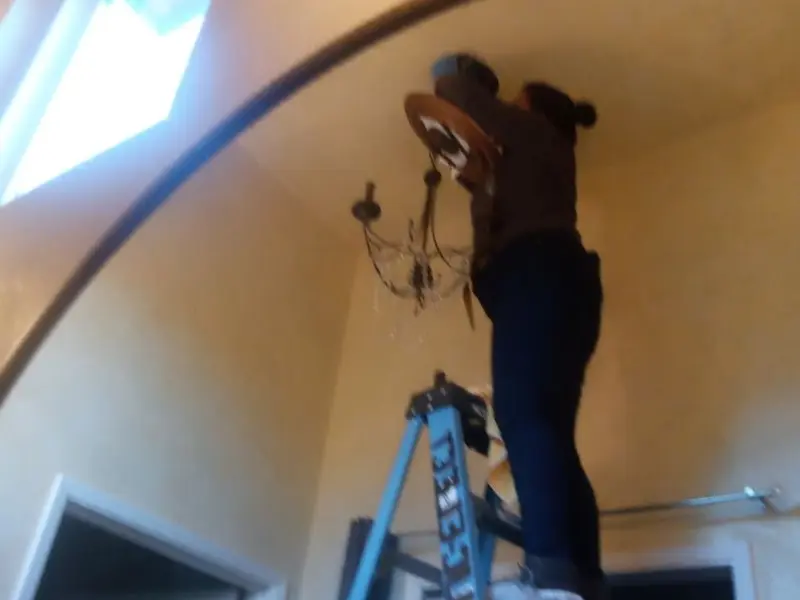 Electrician installing a chandelier in a Birmingham residence